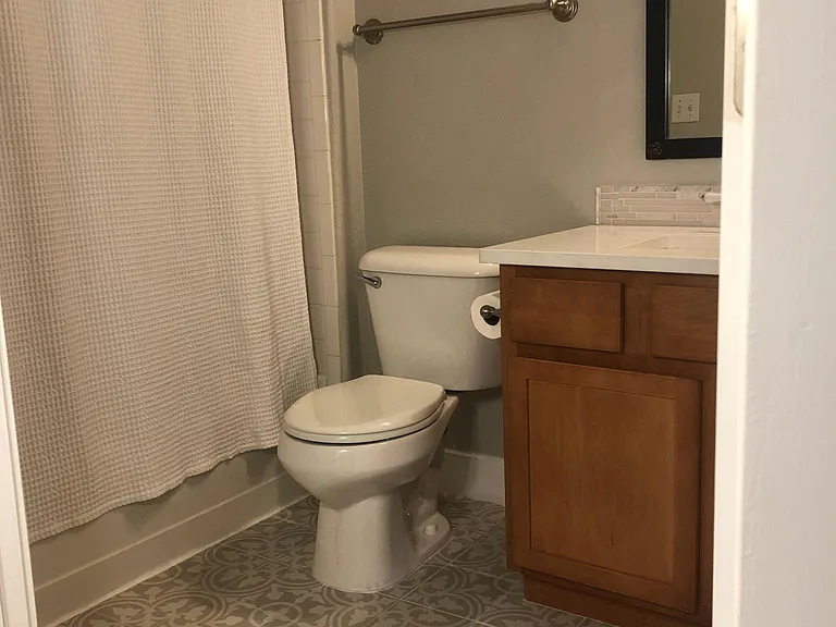 Guest bath features new artisanal floor tiles and in-unit front loading washer and dryer