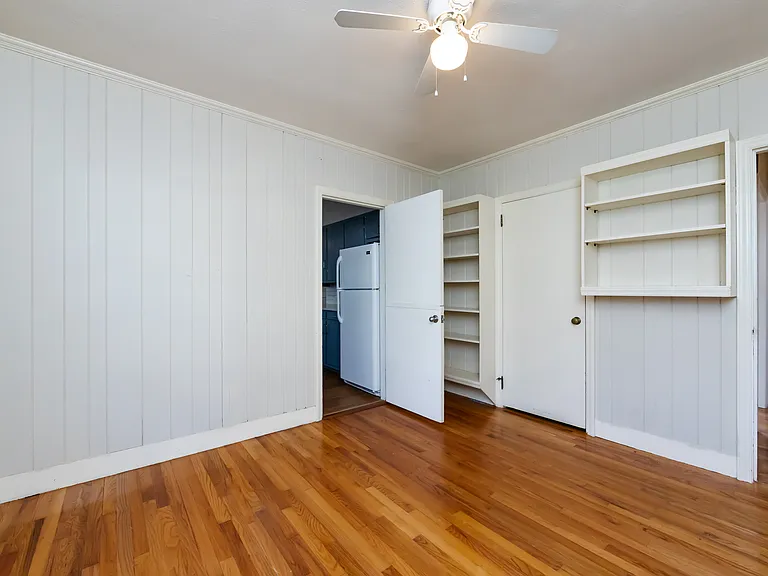 1ST BEDROOM W/ BUILT IN BOOK SHELVES, ENTERS INTO HALLWAY AND KITCHEN, TWO DOORS