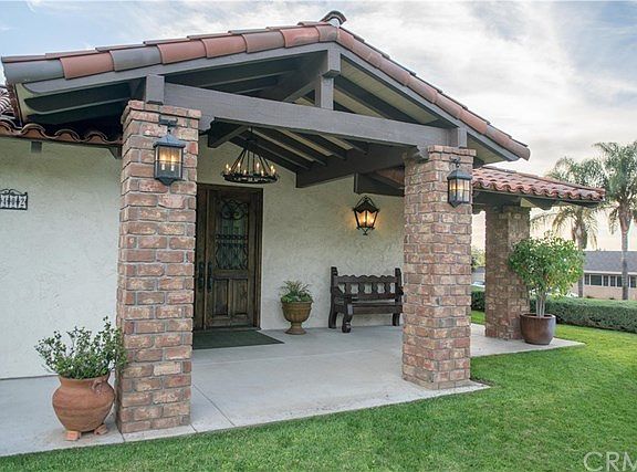 Rustic brick pilasters, gorgeous custom entry doors, designer wrought-iron lighting fixtures, classi