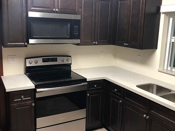 Brand new kitchen with quartz countertops, stainless appliances, and laminate flooring.
