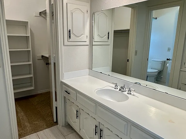 His and Hers primary bathroom with vanity, tile floors and each with their own closet