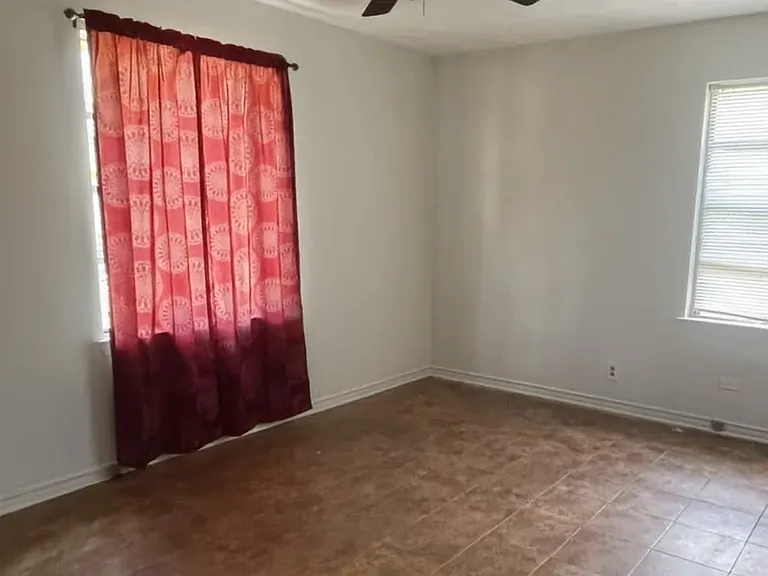 Bright and airy primary bedroom featuring easy-to-clean flooring, a ceiling fan for comfort, and plenty of space for a large bed and furniture.