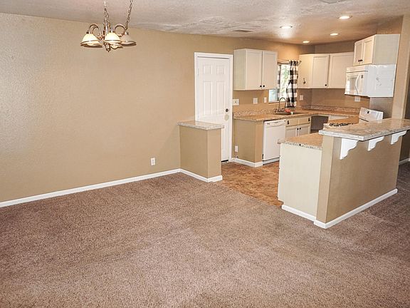 Kitchen with breakfast bar, dishwasher, oven with range, and microwave. Dining area next to kitchen