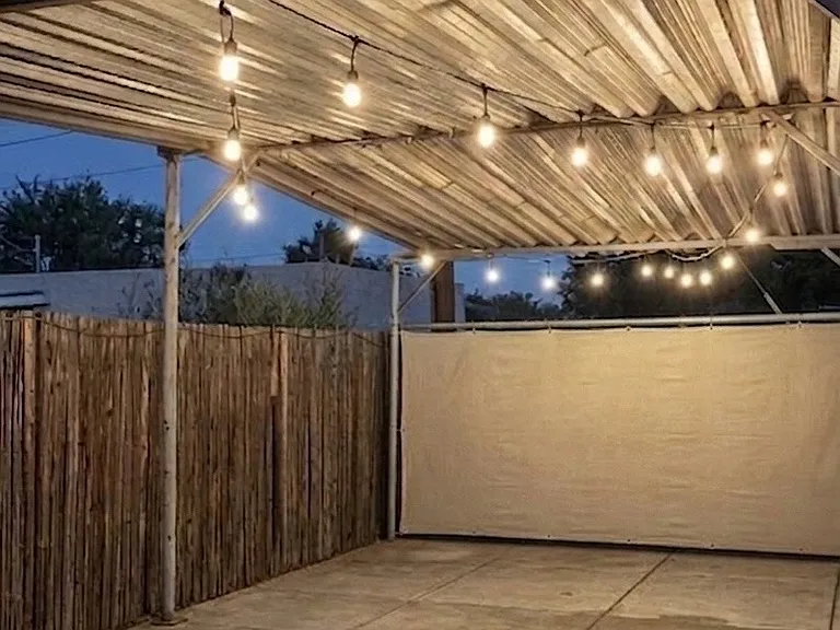 Covered patio in backyard with hanging bistro lights, a great space for outdoor dining when the weather is nice