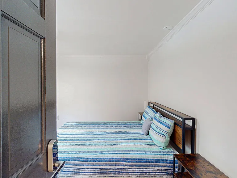Private bedroom with a full bed, headboard shelving, and neutral walls for easy furnishing.