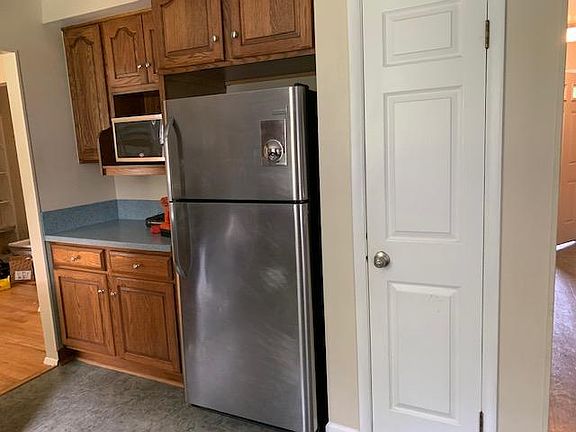 Kitchen with microwave and fridge with ice maker. Pantry next to fridge.