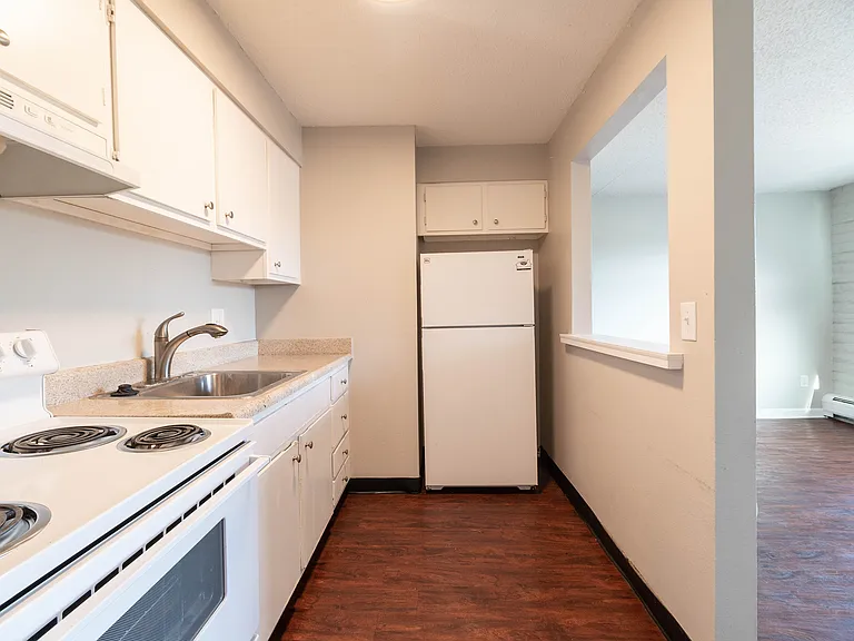 Bright and welcoming kitchen with modern white cabinetry, sleek countertops, and wood-style flooring, perfect for culinary creativity.