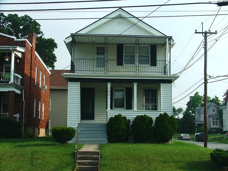 Front of building view with front porch. Parking with garage behind house with large deck.