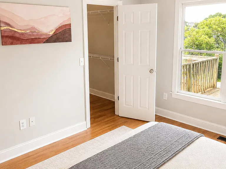 Large ensuite with hardwood floors, ceiling fan, and a wide window view, plus a walk-in closet for convenient storage.