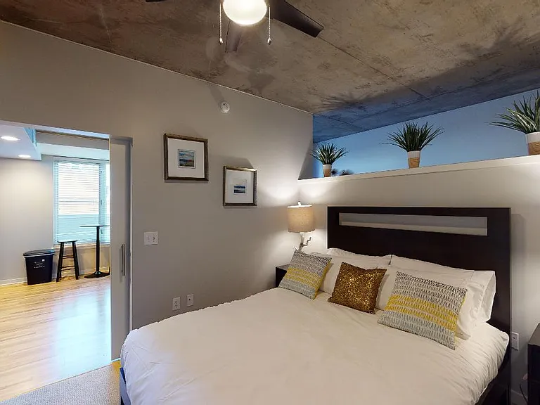 Spacious apartment bedroom with attached bathroom and plush carpet flooring.