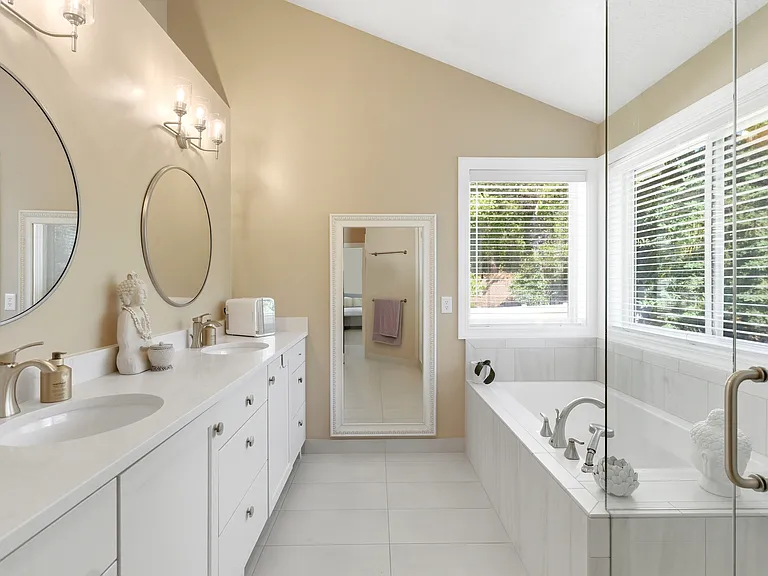 Luxurious primary bath featuring dual vanities, a soaking tub, and separate shower.