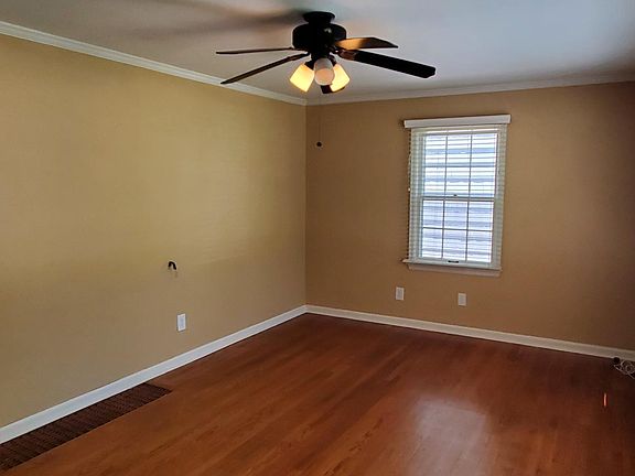 Living room has hardwood floors, ceiling fan. Opens directly to kitchen.