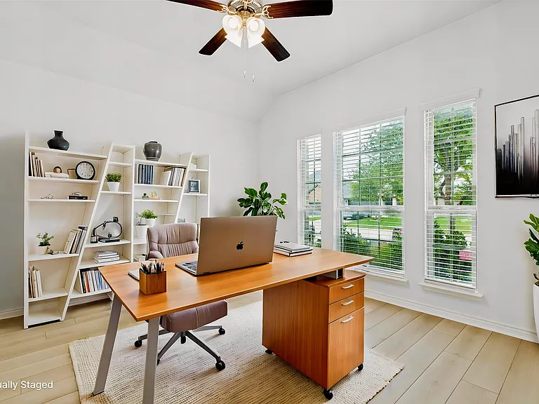 Bright interior room featuring wood-finish flooring, vaulted ceilings, and three tall windows with horizontal blinds