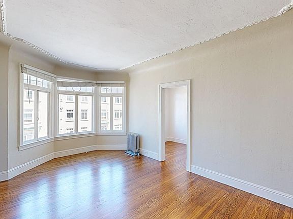 Spacious room with wood-like flooring and a large window offering natural light