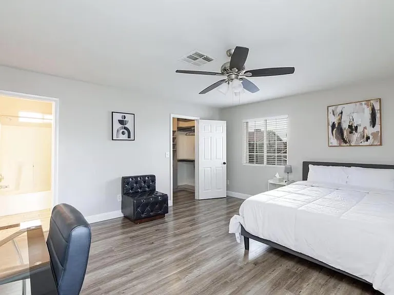 Spacious bedroom with wood-look flooring, ceiling fan, large window, and an open closet for easy storage.