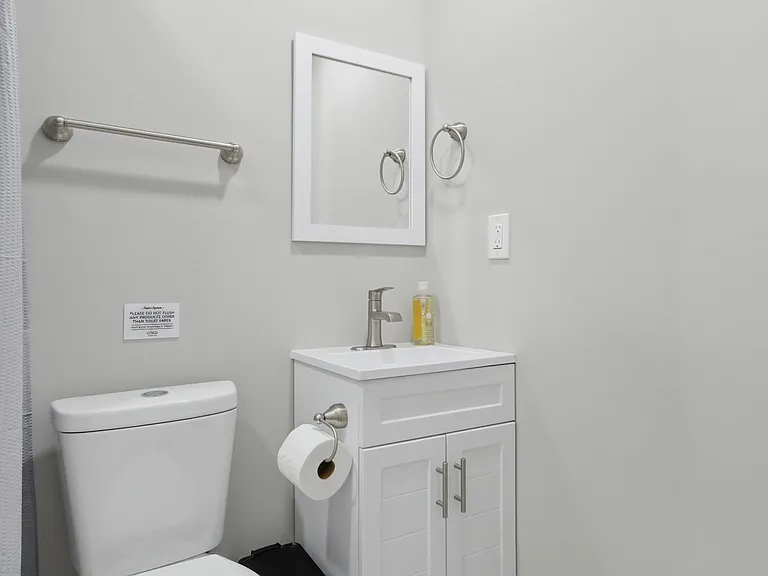 Half bath with a vanity sink, mirror, towel bar, and neutral finishes for convenient everyday use.