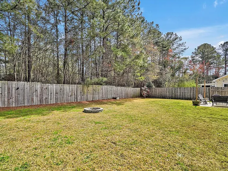 Privacy fenced in backyard with patio and fire pit.