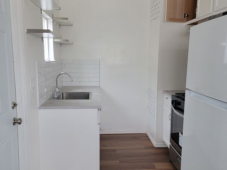 Kitchen with deep sink basin, a fairly new stove and fridge also rustic light fixture.