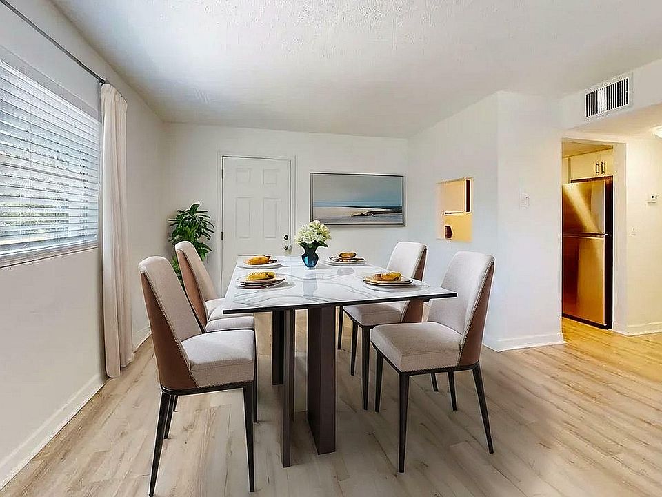 Chic dining area with a modern table set for four, featuring neutral tones, elegant decor, and abundant natural light.