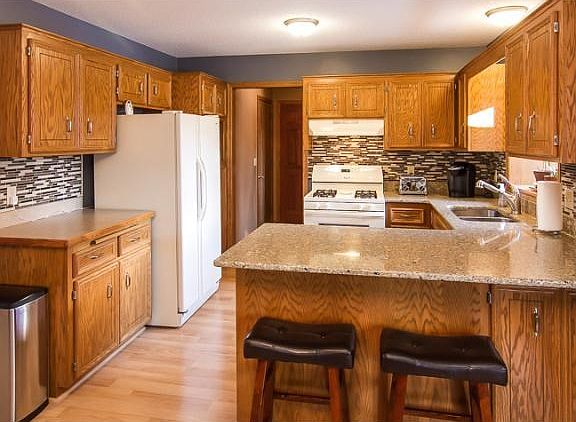 Bright and open kitchen with granite counter tops and tile back-splash. Included breakfast bar.