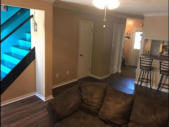 Downstairs living room looking towards the kitchen, laundry room, half bathroom and back door. (Furniture not included! Currently repainted white.)