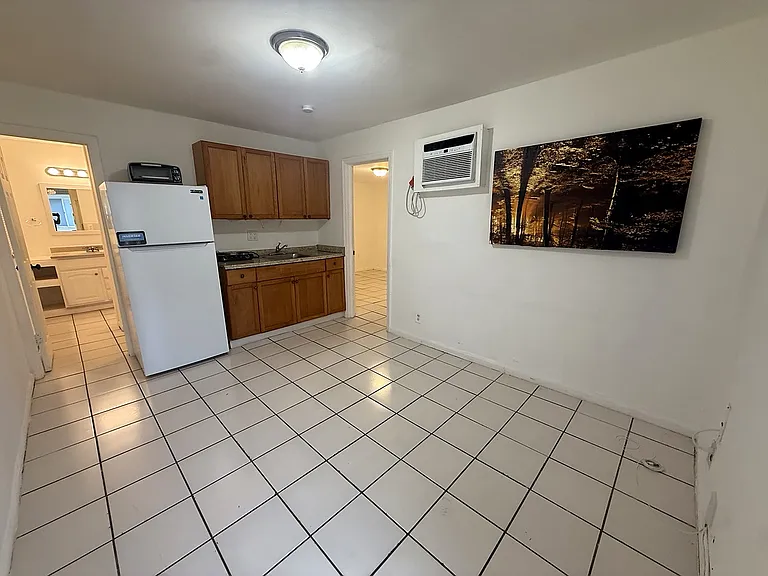 Wide view of the bright living area and kitchenette, with tile flooring throughout and plenty of open space for a comfortable living setup.