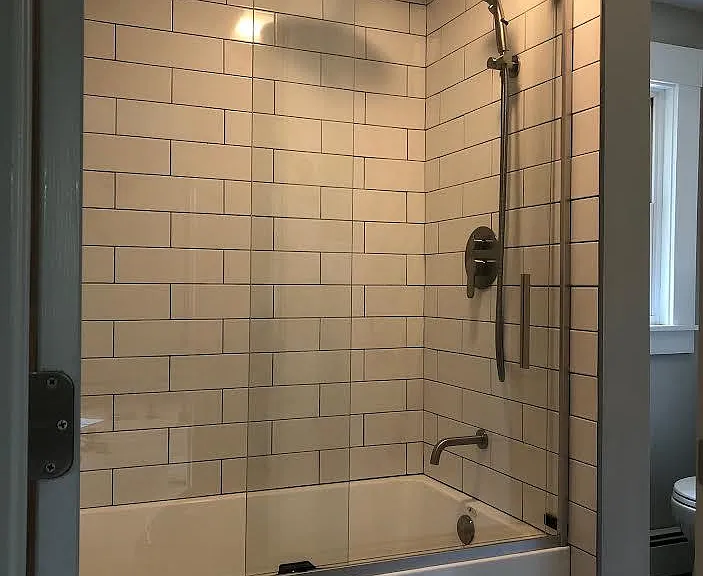 All new tiled bath with rainfall shower head, handheld sprayer, and double sliding glass door - coated for easy cleaning.