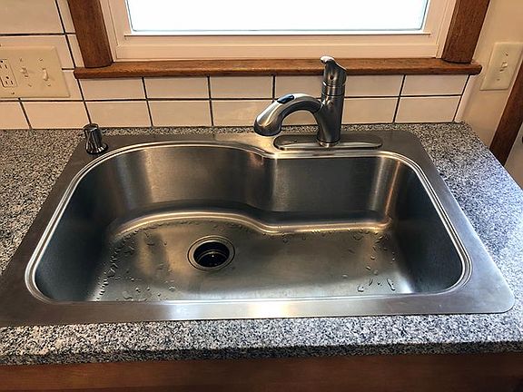 Deep, single-bowl stainless steel sink with soap dispenser,