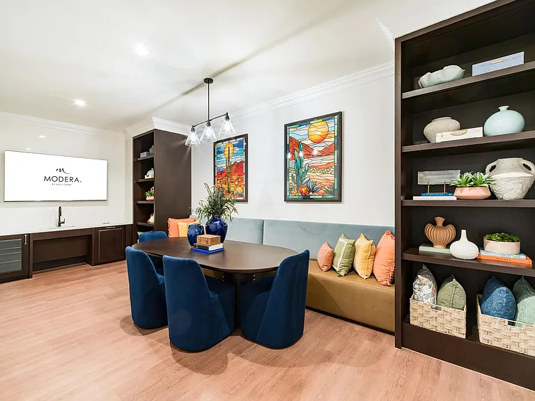 Community dining nook with built-in banquette seating, curated shelving, and a shared table designed for casual meals and small gatherings.