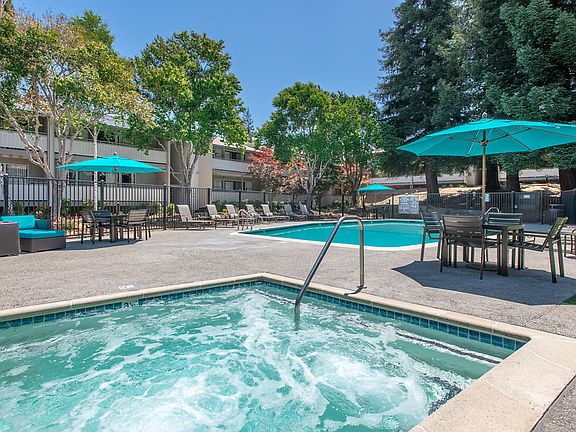 Swimming pool and spa surrounded by lounge chairs.