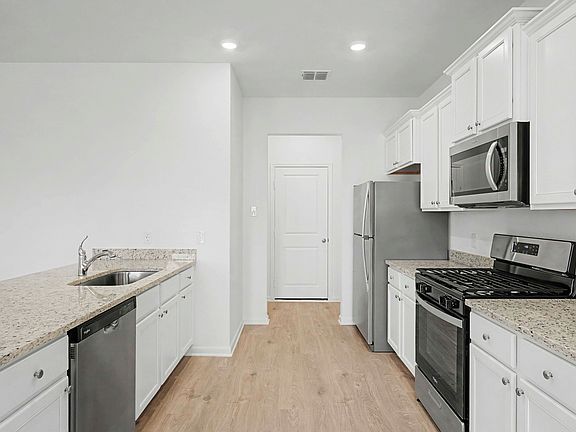 Chef-ready kitchen with stainless steel appliances, granite countertops, and white cabinetry.