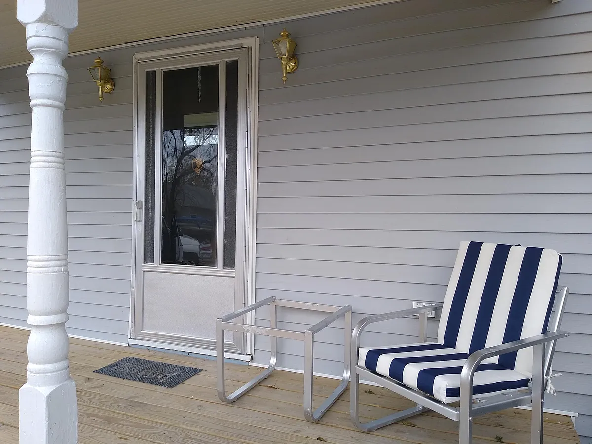 Front porch with patio furniture and end table with dusk/dawn automatic lights. - 1609 Holland St