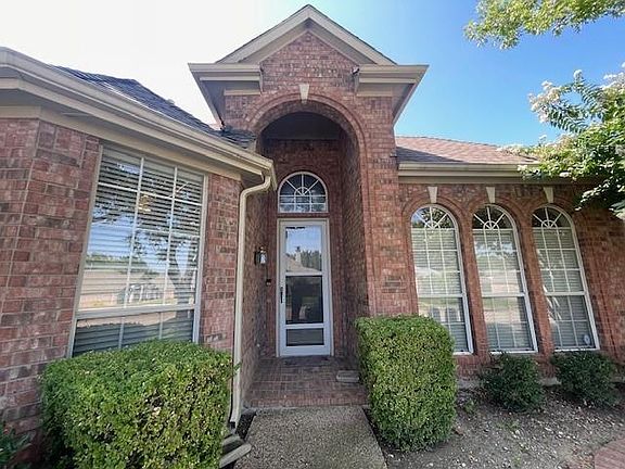 Entrance to property featuring brick siding and roof with shingles