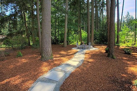 Quaint walkways and firepit with towering evergreens
