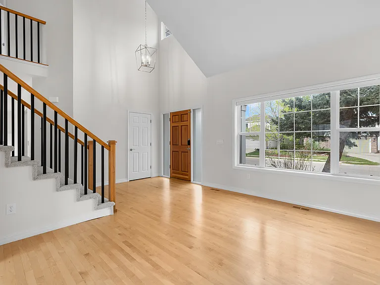 The front door opens into a spacious front living/sitting area filled with natural light and warm hardwood floors.