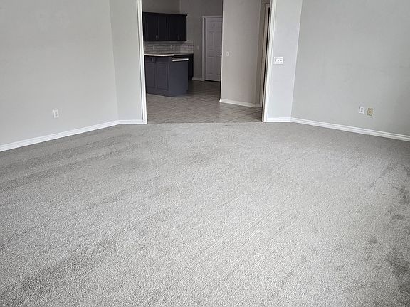 Spacious living room with fresh carpet and an open layout that flows directly into the kitchen and dining areas.