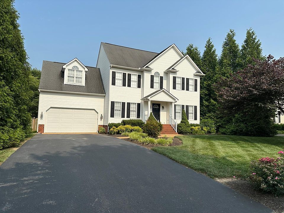 Front of house with paved driveway and professionally landscaped yard