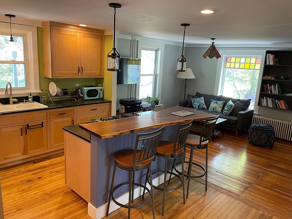 Large open kitchen with custom Vermont maple cabinetry, live edge walnut bar top, vermont stone countertops, high end gas stove range, under-cabinet lighting, farmhouse sink, dishwasher, new furnishings