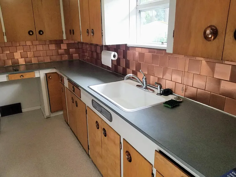 The kitchen enjoys plenty of storage and a window above the sink. And the copper backsplash and hardware are original.