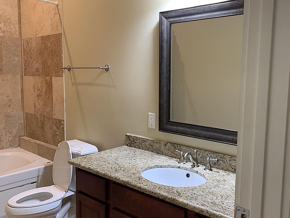 Single granite topped cherry wood cabinet offers maximum of storage in this full bathroom