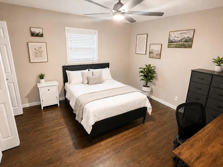 Furnished bedroom with a full bed, nightstand, dresser, and dedicated desk space, plus hardwood floors and a ceiling fan.