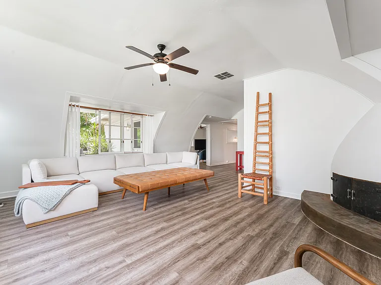 Additional view of the main living area with vaulted ceilings and decorative non-functioning fireplace.