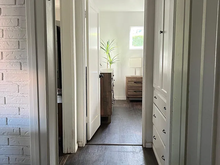 View of hallway from bathroom 1 facing bedroom 1. Bedroom 2 is on the left and kitchen and living room are on the righ