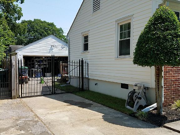 Side of house with iron gate and garage in the back yard.