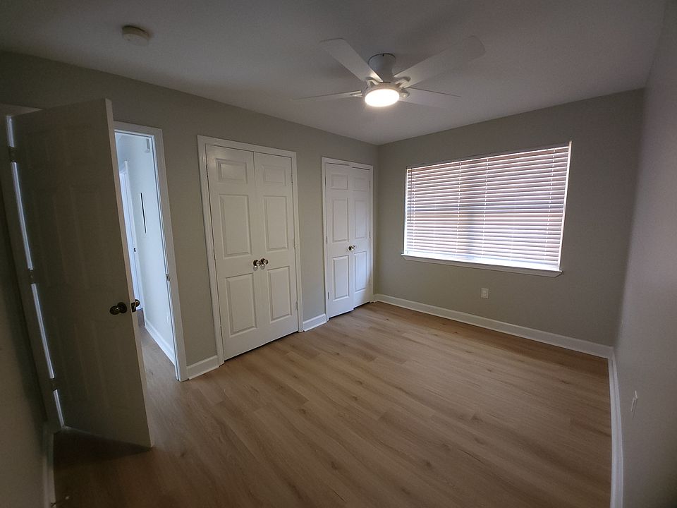 BEDROOM #2, DOUBLE CLOSETS AND CHRYSTAL HARDWARE. LARGE WINDOW WITH PRIVACY FENCE AND WOODED LOT VIEW BEHIND.