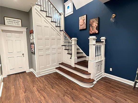 Grand staircase featuring white paneling and dark wood-finish treads