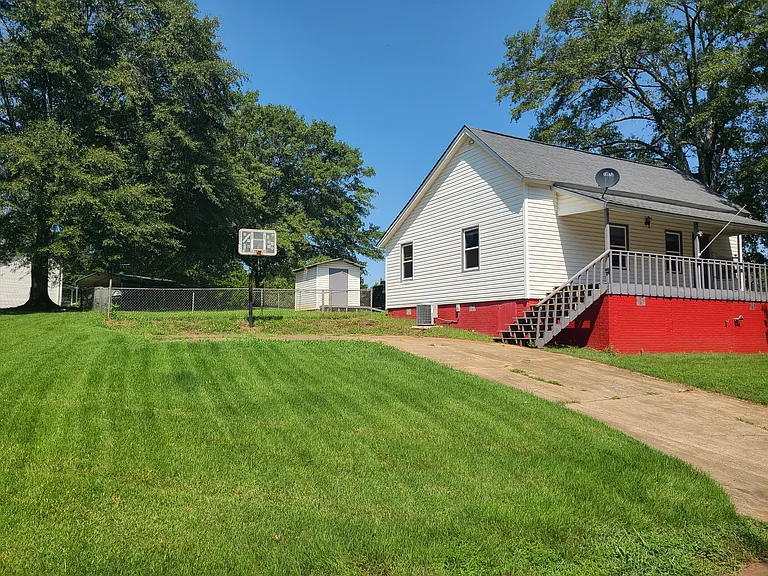 Driveway, basketball goal, fence, and shed