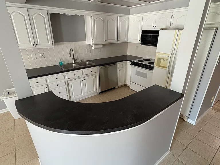 Kitchen with fresh paint on walls & cabinets. New dishwasher in 2025. Refrigerator, stove and microware are original but work well.