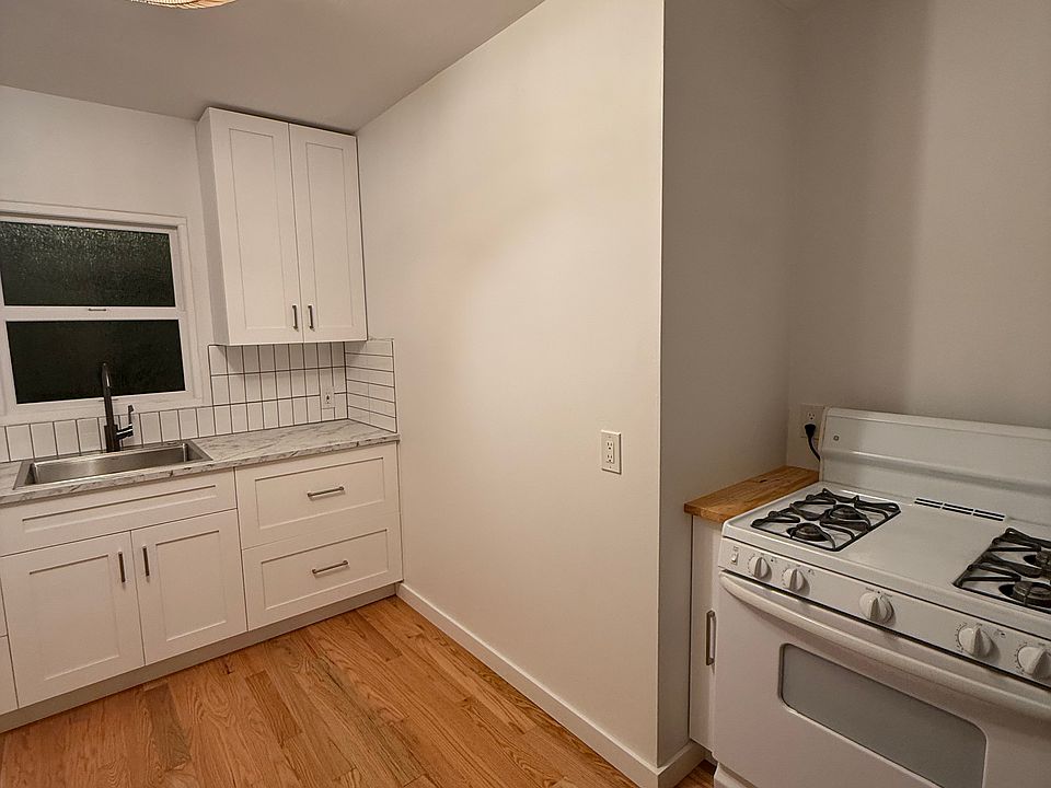 Newly renovated kitchen including a pullout spice rack, gas stove, 'fandolier', and hardwood floors.