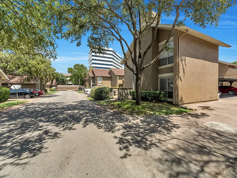 Tree-lined residential street view at Watersong Villas Apartments with shaded parking areas and peaceful North Dallas community setting.